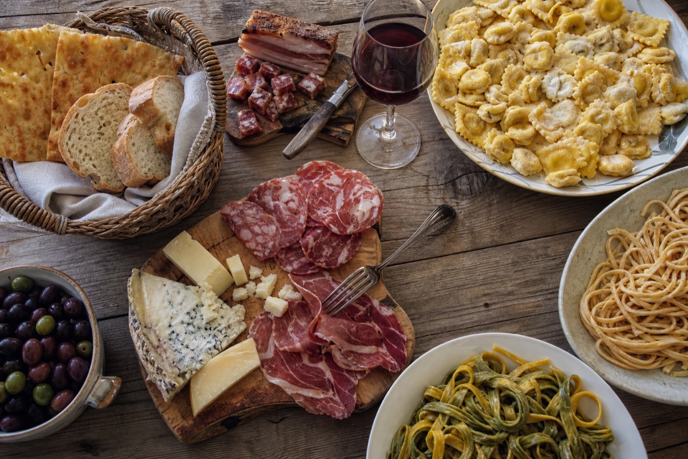 Specialty food shop window in Parma displaying Parmigiano Reggiano wheels and Prosciutto di Parma
