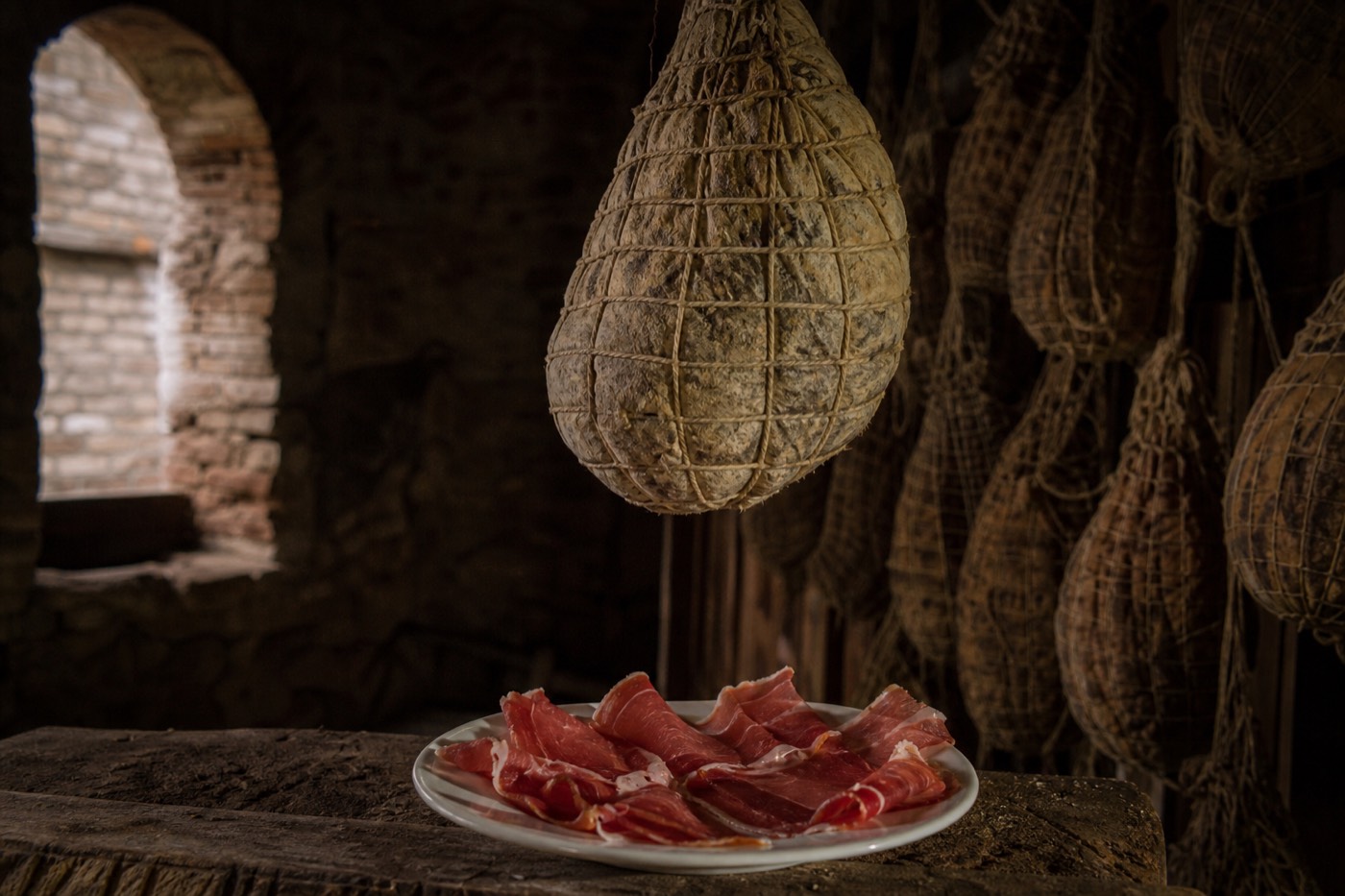 Culatello di Zibello cured meat hanging to age in a specialist Parma salumeria